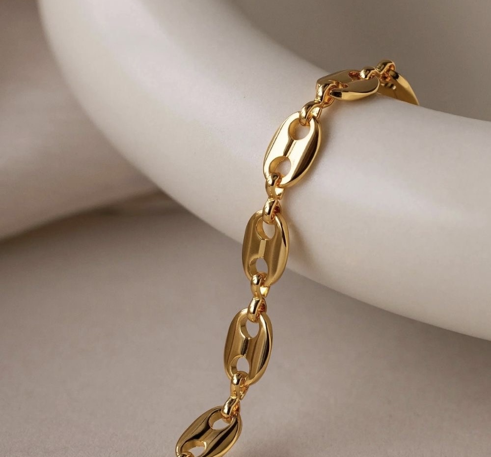 Anillo y collar dorados sobre bandeja de piedra